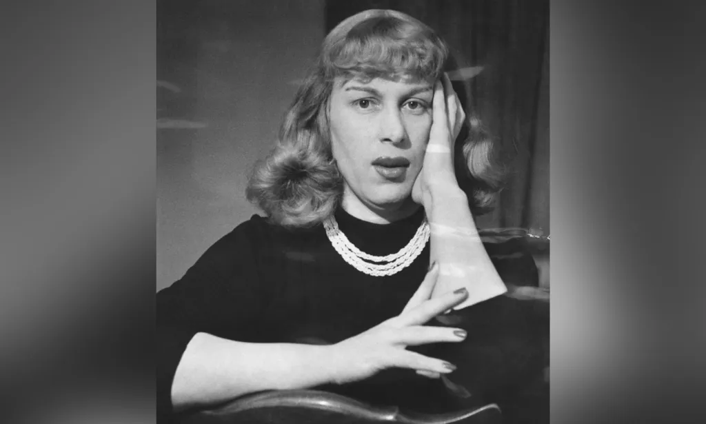 British trans woman Roberta Cowell wears a dark long-sleeved top and necklace while she poses for a photo