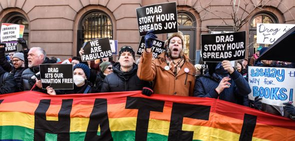Counter-protestors hold up a rainbow banner and signs in support of the LGBTQ+ community while standing in solidarity with a Drag Story Hour event