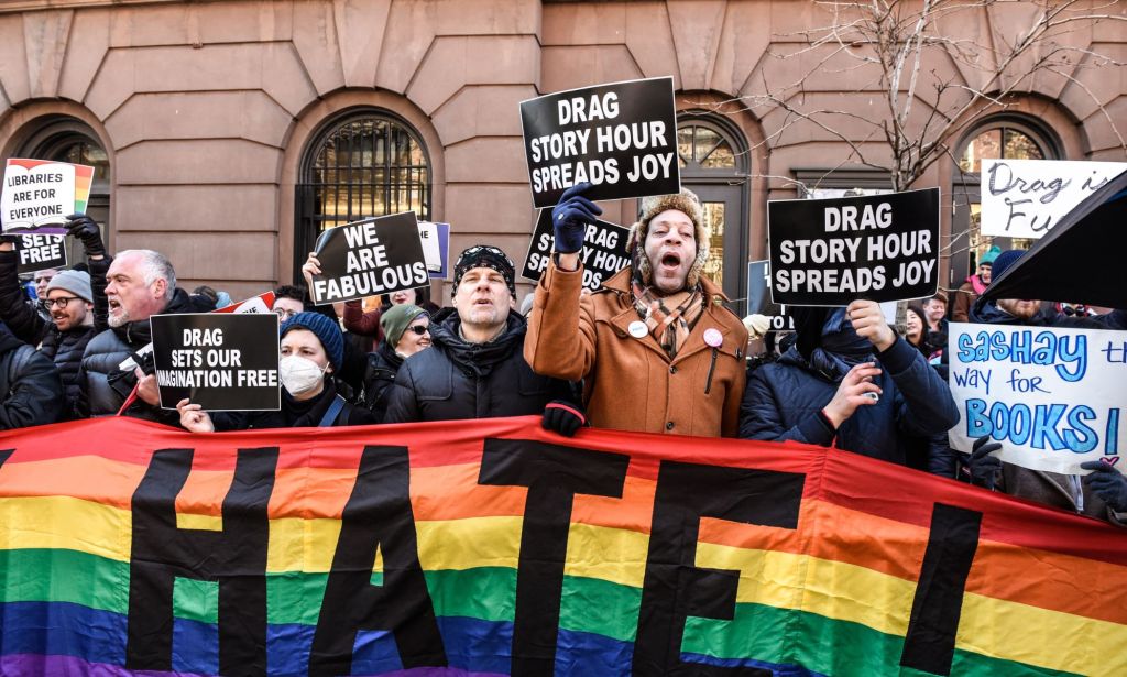 Counter-protestors hold up a rainbow banner and signs in support of the LGBTQ+ community while standing in solidarity with a Drag Story Hour event