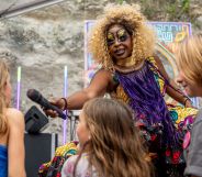 A Black drag queen stands on stage as she holds out a microphone to kids in the audience at an event in Texas as Republican lawmakers try to ban such kid-friendly events