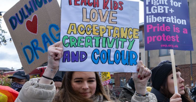 Protester holding a placard which says: teach kids love, acceptance, creativity and colour