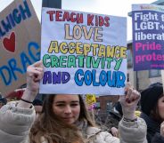 Protester holding a placard which says: teach kids love, acceptance, creativity and colour