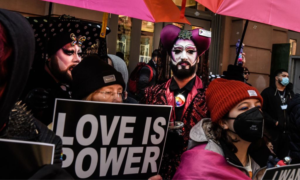 A person holds up a sign reading "Love is power" at a protest attended by LGBTQ+ people and allies in support of Drag Story Hour