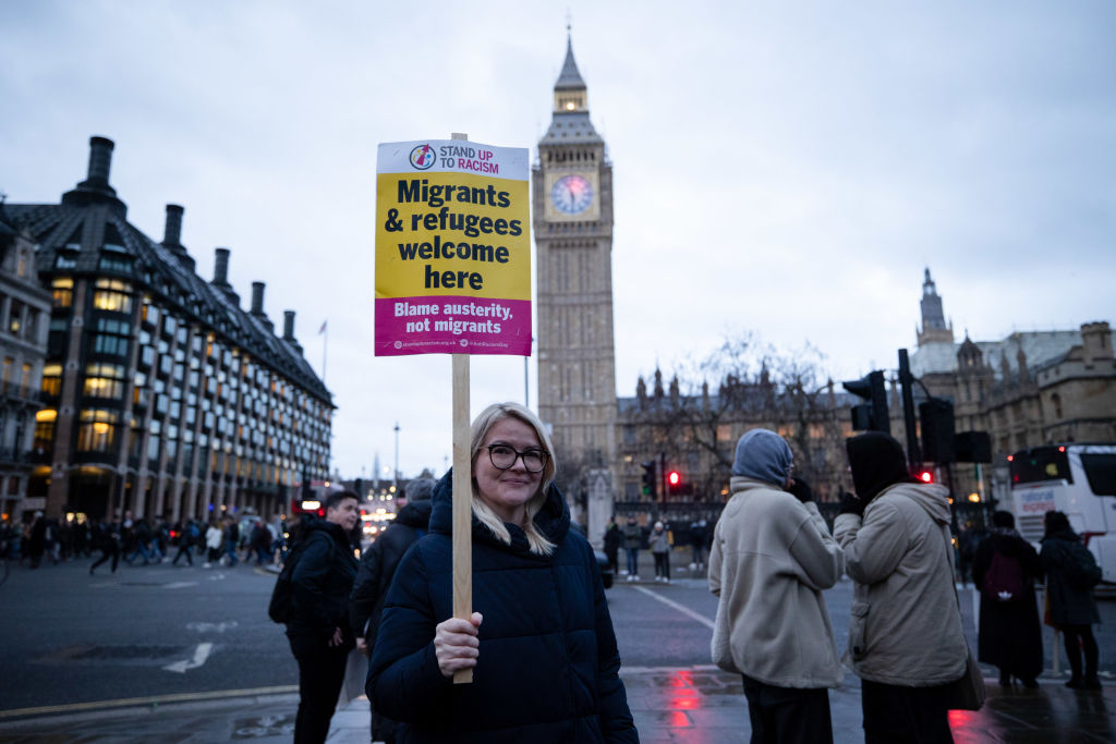 A protester is seen holding a placard during the rally at Parliament Square. The sign says "Migrants and Refugees welcome here"