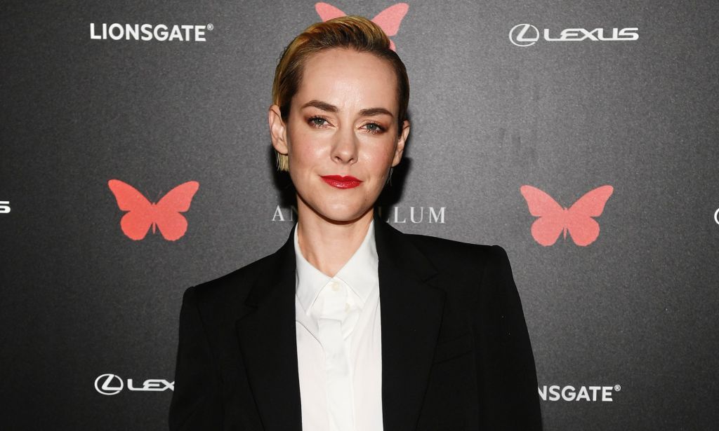 Actor Jena Malone wears a white shirt and dark jacket as she poses for the camera