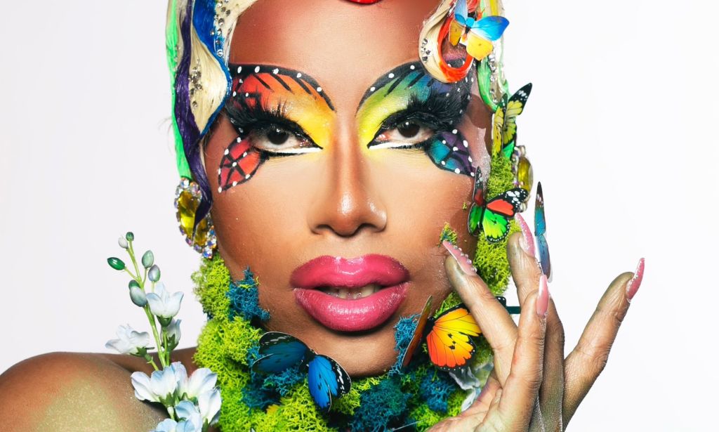 Texas-based drag queen Kylee Ohara Fatale poses for the camera while wears rainbow butter-fly themed makeup with butterfly props and flora in her makeup