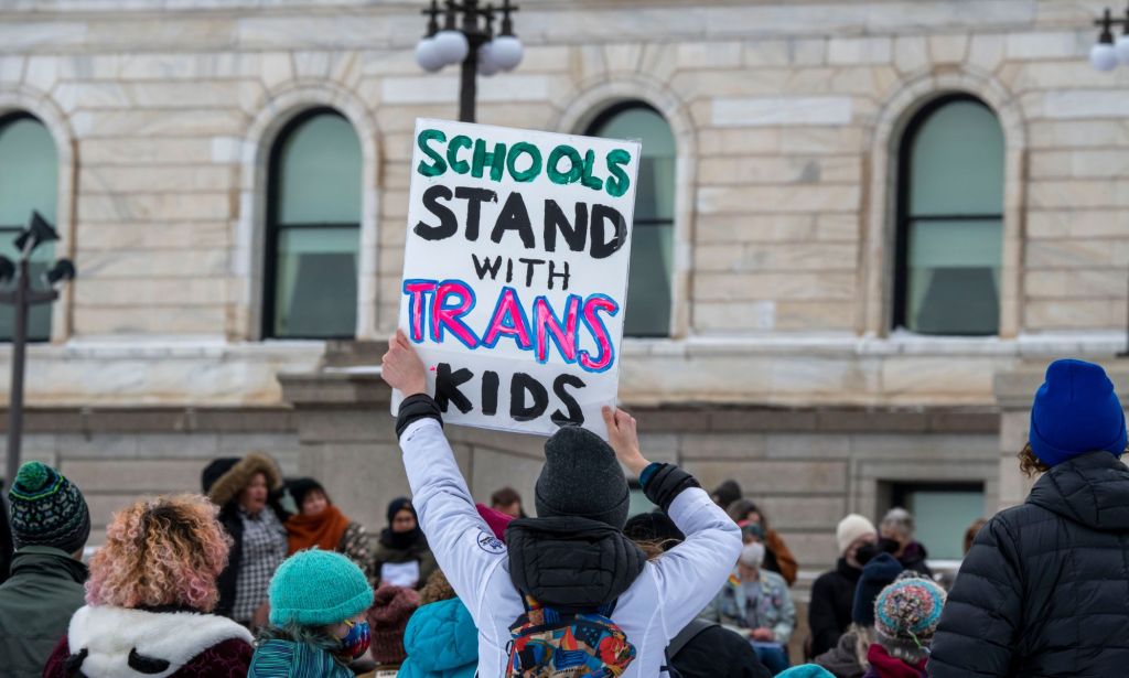 A person holds up a sign reading 'Schools stand with trans kids' during a protest in support of the trans and LGBTQ+ community in the USA
