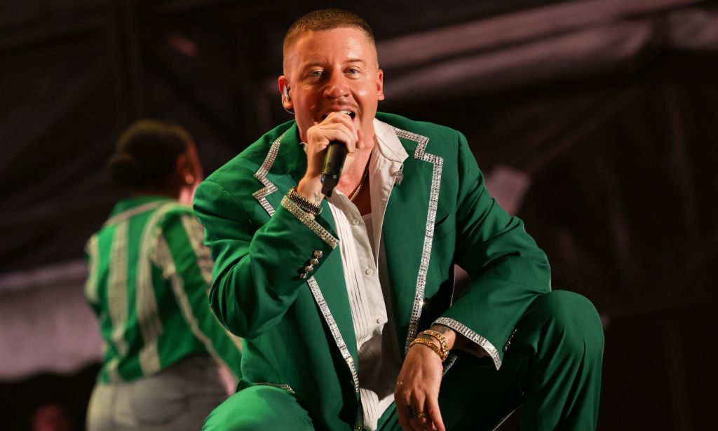 American rapper Macklemore wears a green and white outfit as he performs on stage