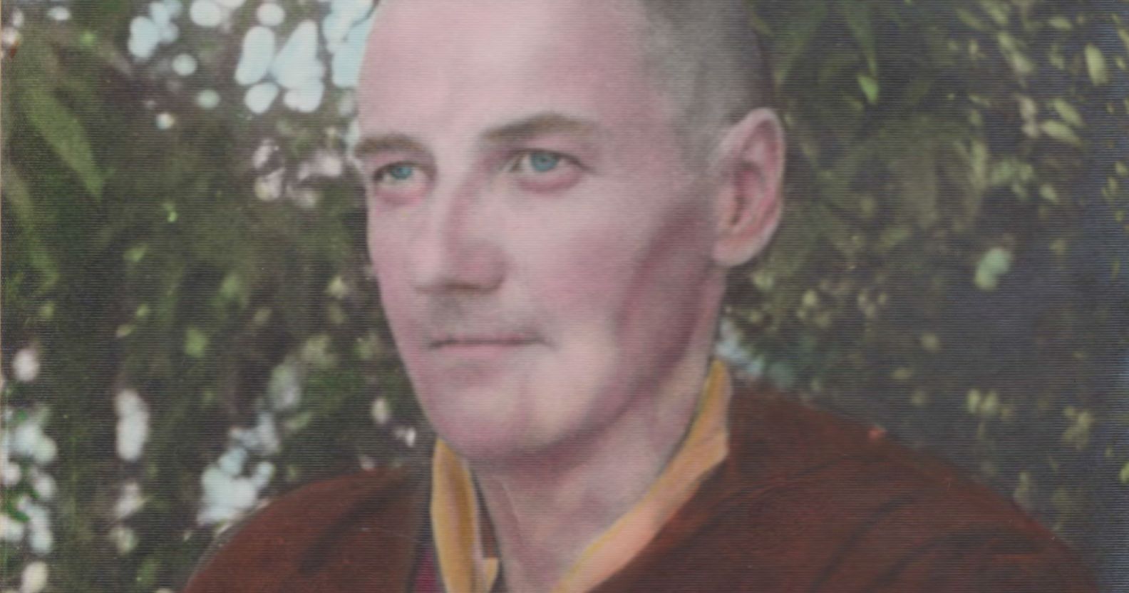 A picture of trans trailblazer Michael Dillon wearing red and yellow coloured Buddhist monk robes