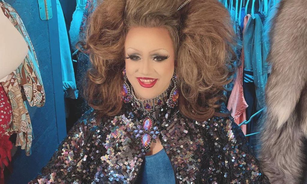 Kentucky drag queen Poly Tics, who is also an LGBTQ+ activist, wears a sparkly top and blue dress as she poses for a picture