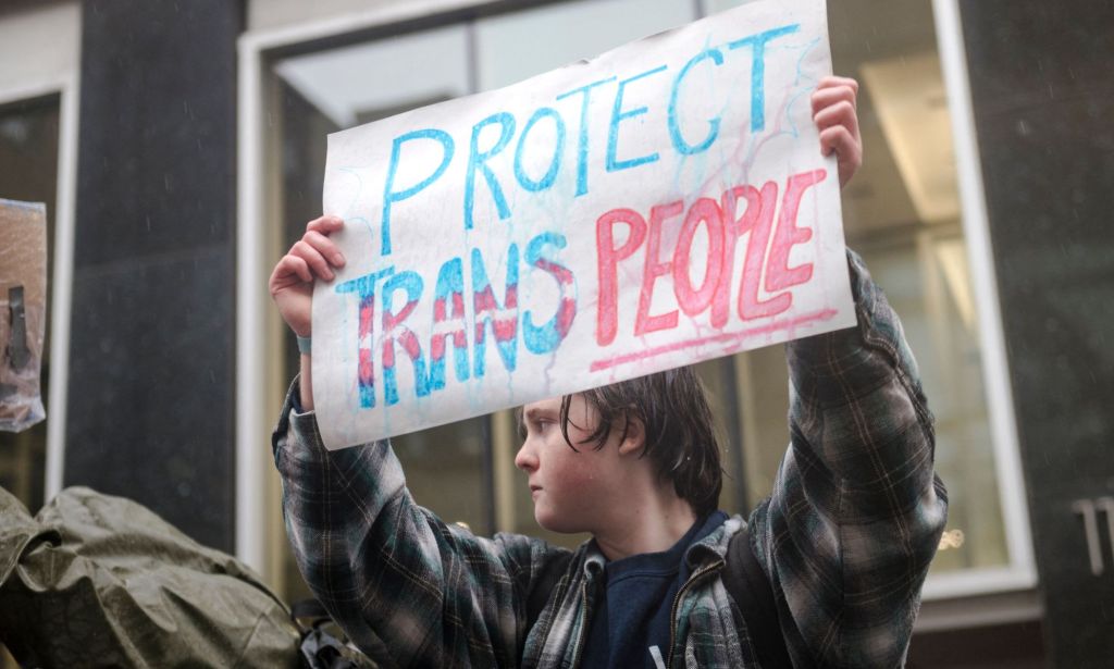 A person holds up a sign reading "Protect trans people" during a protest in support of the trans community held up LGBTQ+ people and allies