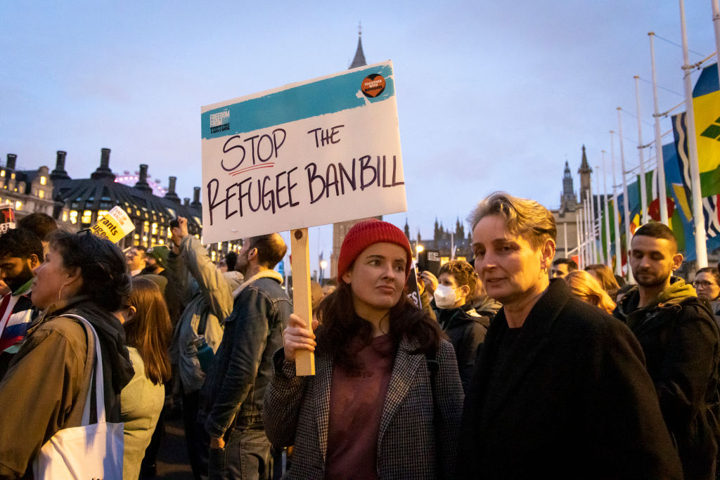 A person holds a sign which says "stop the refugee ban bill" at a protest in London. 