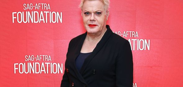 Trans actor and comedian Suzy Eddie Izzard wears a dark shirt and dark jacket as she smiles for the camera at an event