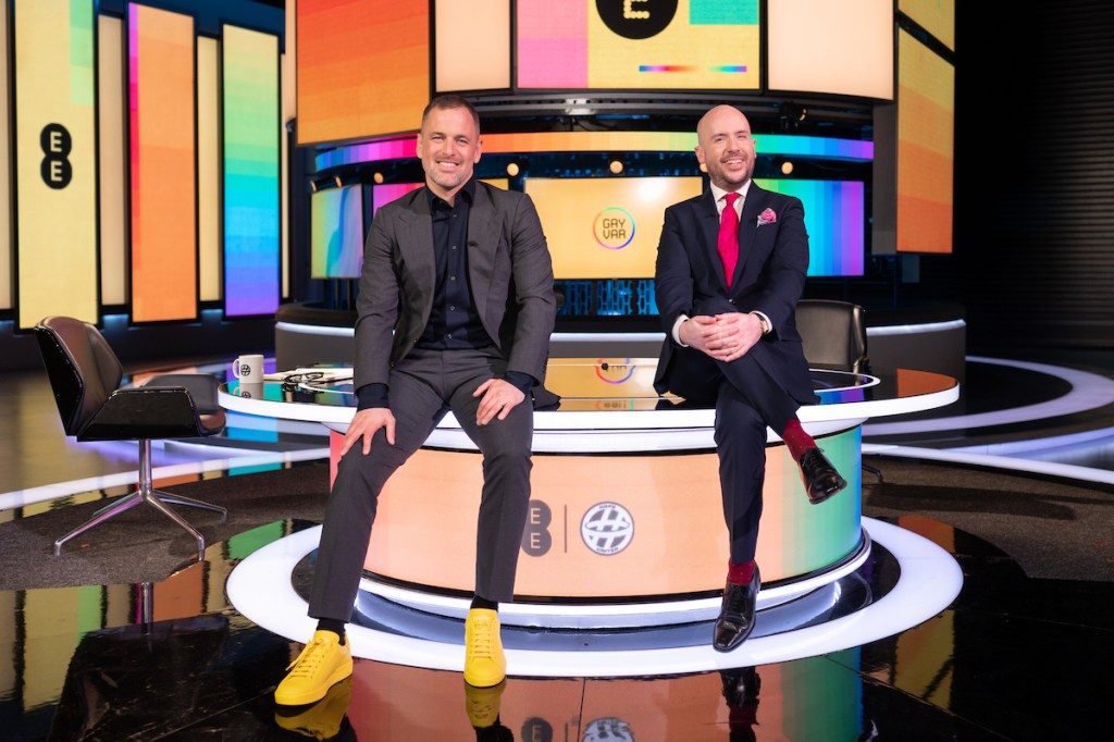 Joe Cole is pictured on the left and Tom Allen is pictured on the right. They are sitting on a table in a colourful studio.
