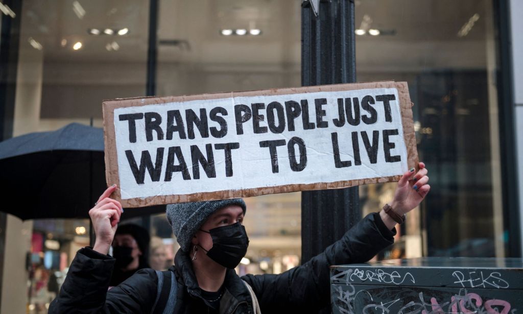 A person holds up a sign reading "Trans people just want to live" during a protest in support of the trans community held up LGBTQ+ people and allies