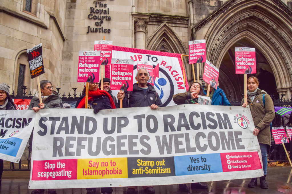 Protesters hold a "Refugees welcome" banner and placards during the demonstration.