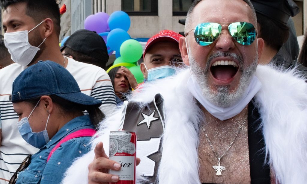 A Pride goer holding a Budweiser can.