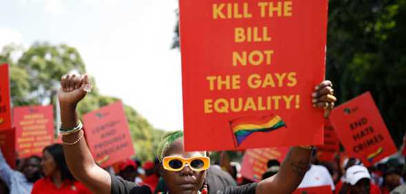 DeLovie Kwagala pictured holding a sign that says "Uganda Kill the bill not the gays equality!".