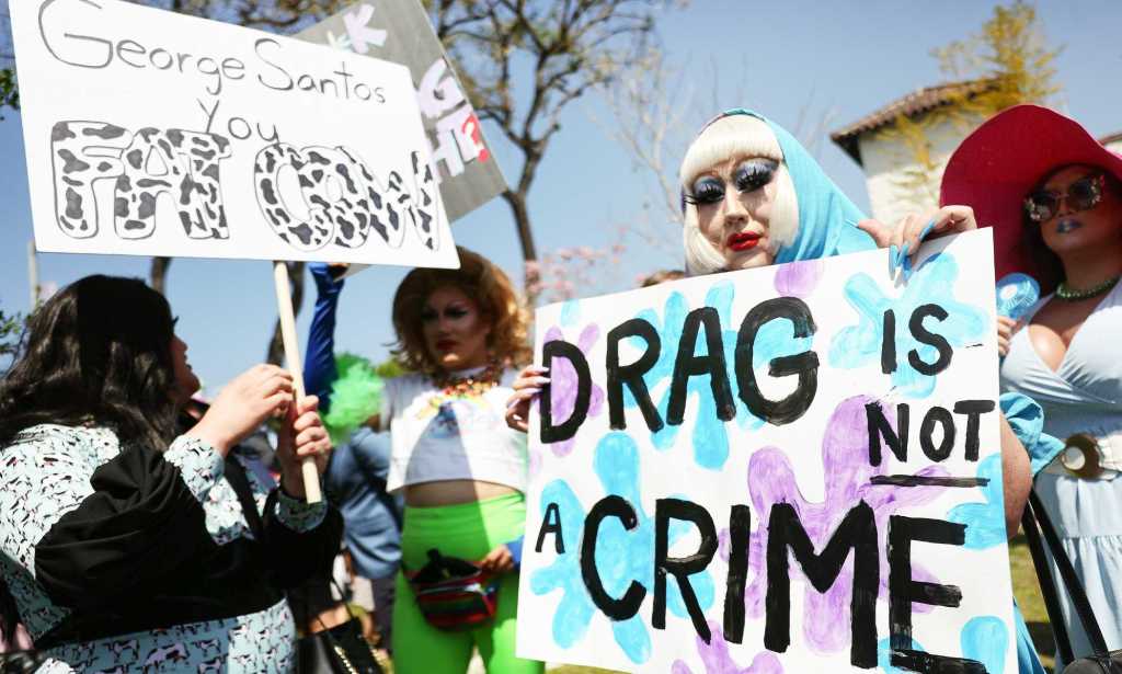 A person holds up a sign reading 'Drag is not a crime' during an LGBTQ+ protest