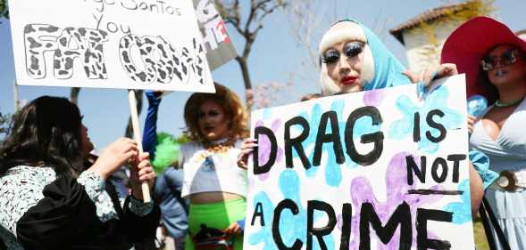 A person holds up a sign reading 'Drag is not a crime' during an LGBTQ+ protest