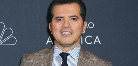 John Leguizamo posing in a plaid suit for a red carpet event.