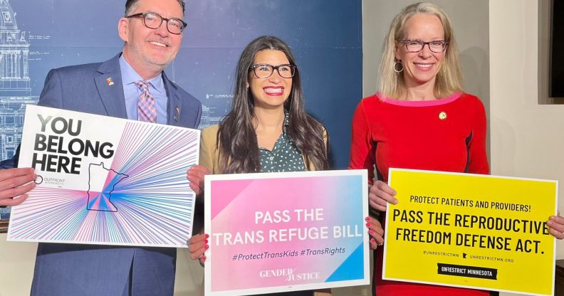 Minnesota lawmakers hold up signs of trans positivity.