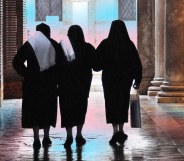 Image shows a group of nuns walking with their backs to the camera, in front of a backdrop of the transgender flag