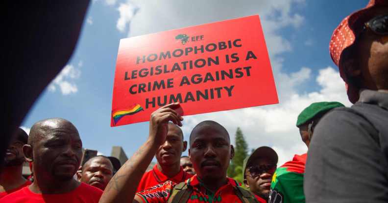 A proptester holds a sign that reads: homophobic legislation is a crime against humanity