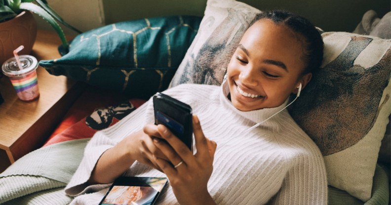 Stock image of a teenager using her mobile phone and smiling