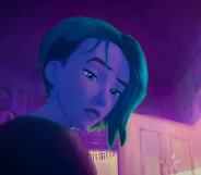 A still from the Spider-Man: Across the Spider-Verse trailer featuring Gwen Stacy with a Protect Trans Kids poster in the background