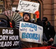 A person in a pro-drag rally holding signs reading 'drag story hour spreads joy'