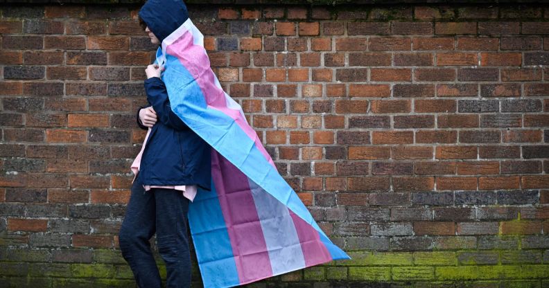 A person holds a trans flag in the rain.