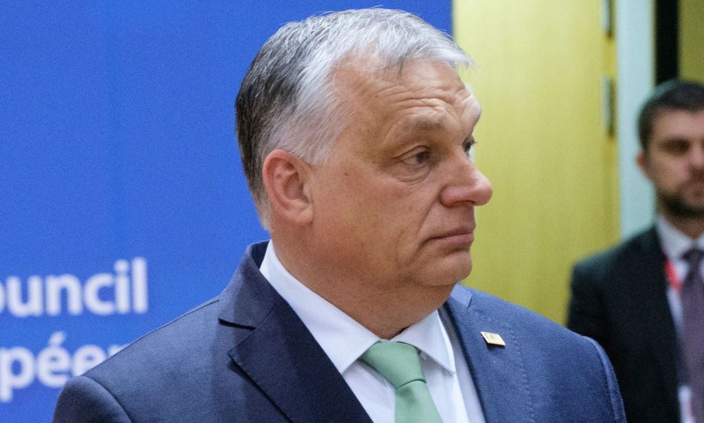 Viktor Orban, wearing a blue suit and teal tie, looks off.