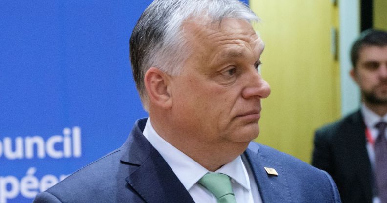 Viktor Orban, wearing a blue suit and teal tie, looks off.
