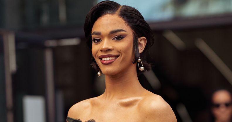 Yasmin Finney wears a black dress, pearl earrings and smiles at the camera.