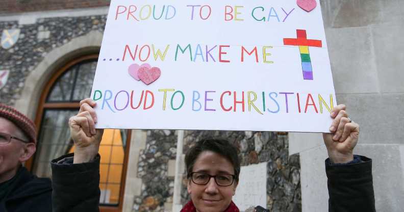 A gay christian holds a sign that reads "proud to be gay, now make me proud to be christian"