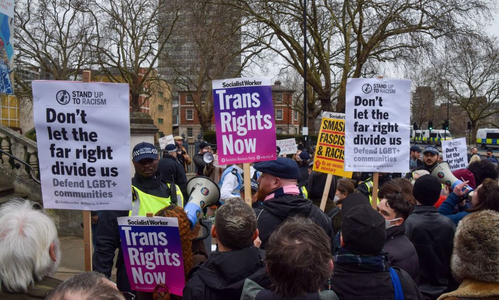People hold up signs reading 'Trans rights now' and to fight back against the far-right during an LGBTQ+ and trans rights protest against the UK government