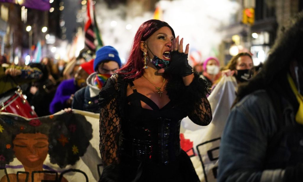 Trans activist Iman Le Caire holds up her hand near her mouth as she speaks during a protest march