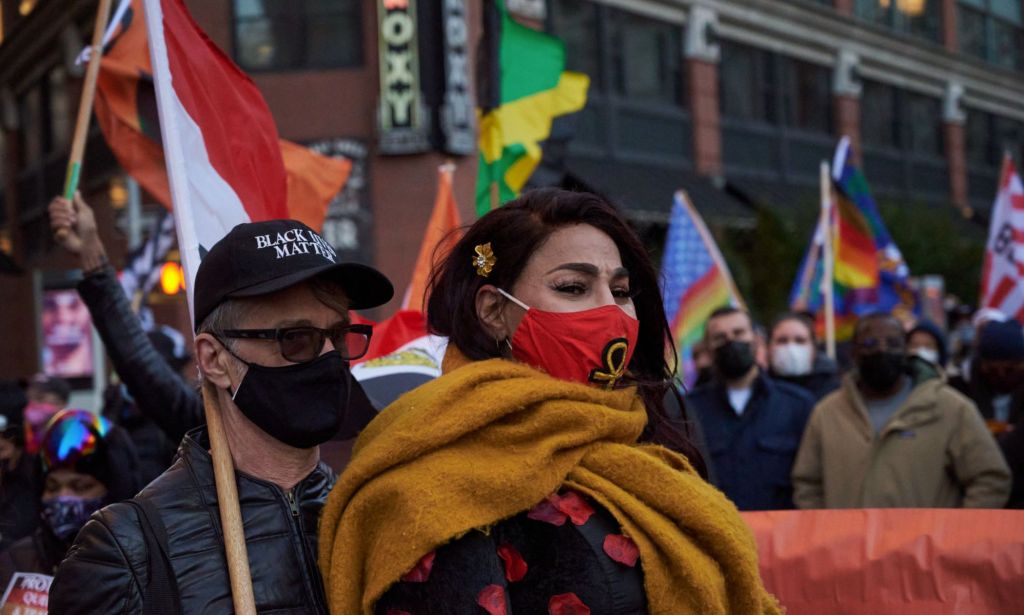Trans activist Iman Le Caire wears a red mask as she stands alongside her husband during a march