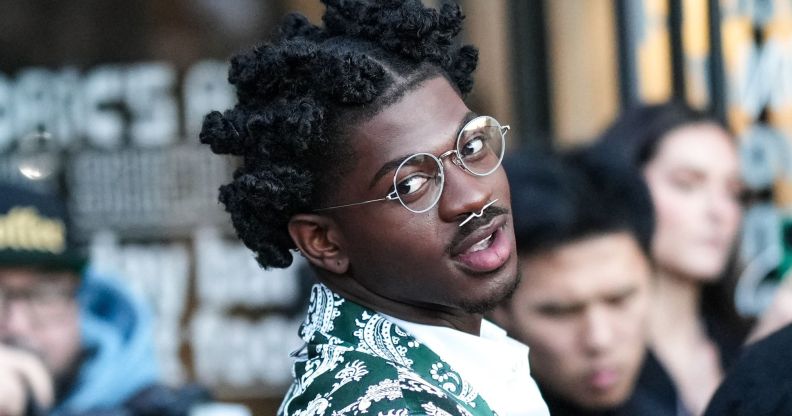 Rapper Lil Nas X wears a green and silver patterned jacket, round silver glasses and a nose piercing