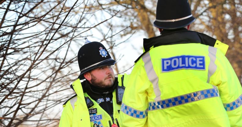 Two police officers wear the yellow, blue and black uniforms associated with law enforcement in England and Wales as they stand at the scene of a crime