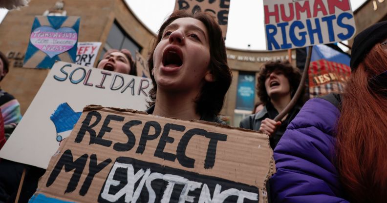 A person holds up a sign reading 'respect my existence' during a protest in favour of trans rights and against the Tory government