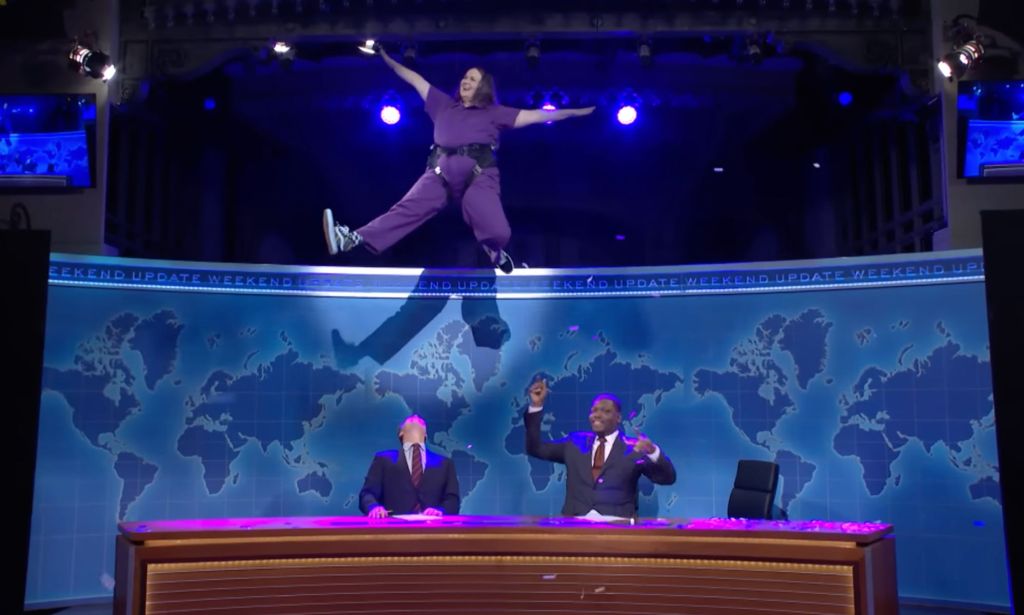 Molly Kearney wears a purple jump suit as they're hosted above fellow SNL castmates during the "Weekend Update" segment where they talked about gender-affirming healthcare and trans rights