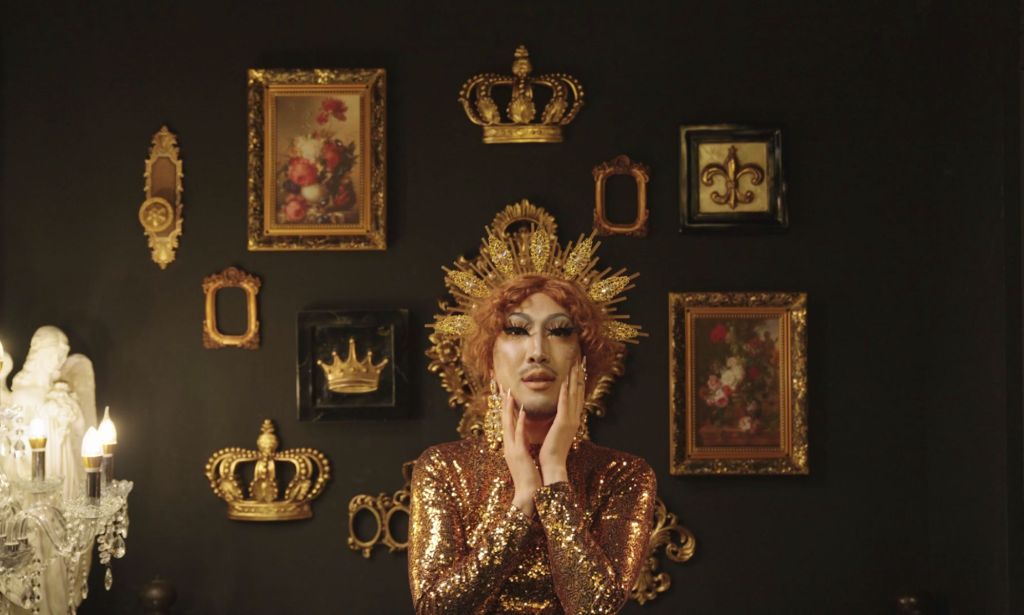 South Korean LGBTQ+ activist Heezy Yang is dressed, as his drag persona Hurricane Kimchi, in a gold outfit with a dark background