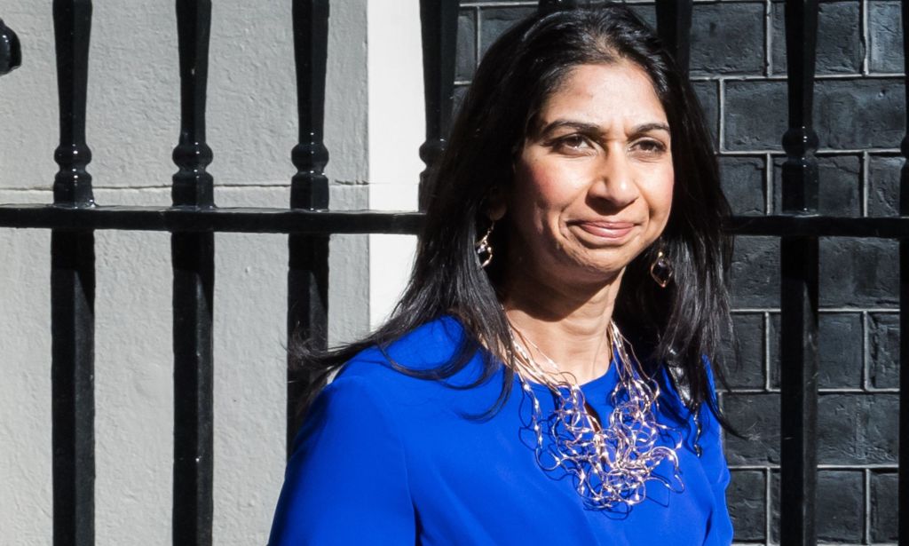 UK home secretary Suella Braverman wears a blue outfit and silver necklace as she steps outside. LGBTQ+ and human rights campaigners have criticised Braverman for her comments about asylum seekers