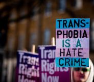 A person holds up a sign in the colours of the trans pride flag (blue, pink and white) reading 'Transphobia is a hate crime' during a protest