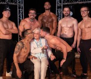 Betty, 92, surrounded by seven members of the Dreamboys cast, who kiss her on the cheek