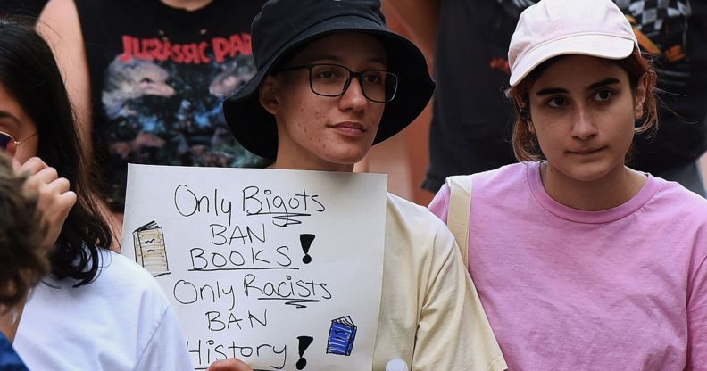A person holds a sign reading "only bigots ban books, only racists ban history."