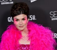 Dylan Mulvaney wears pink feather boa and pink eyeshadow against a black background
