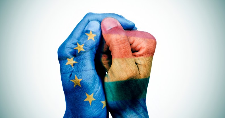 closeup of the hands of a man put together patterned with the flag of the european union and the rainbow flag